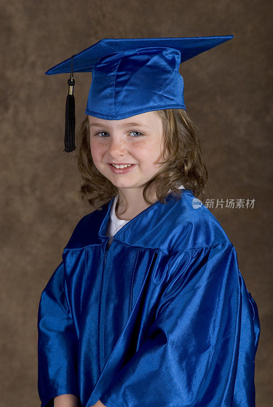 可爱的年轻女孩在长袍和学位帽，毕业肖像幼儿园/幼儿园